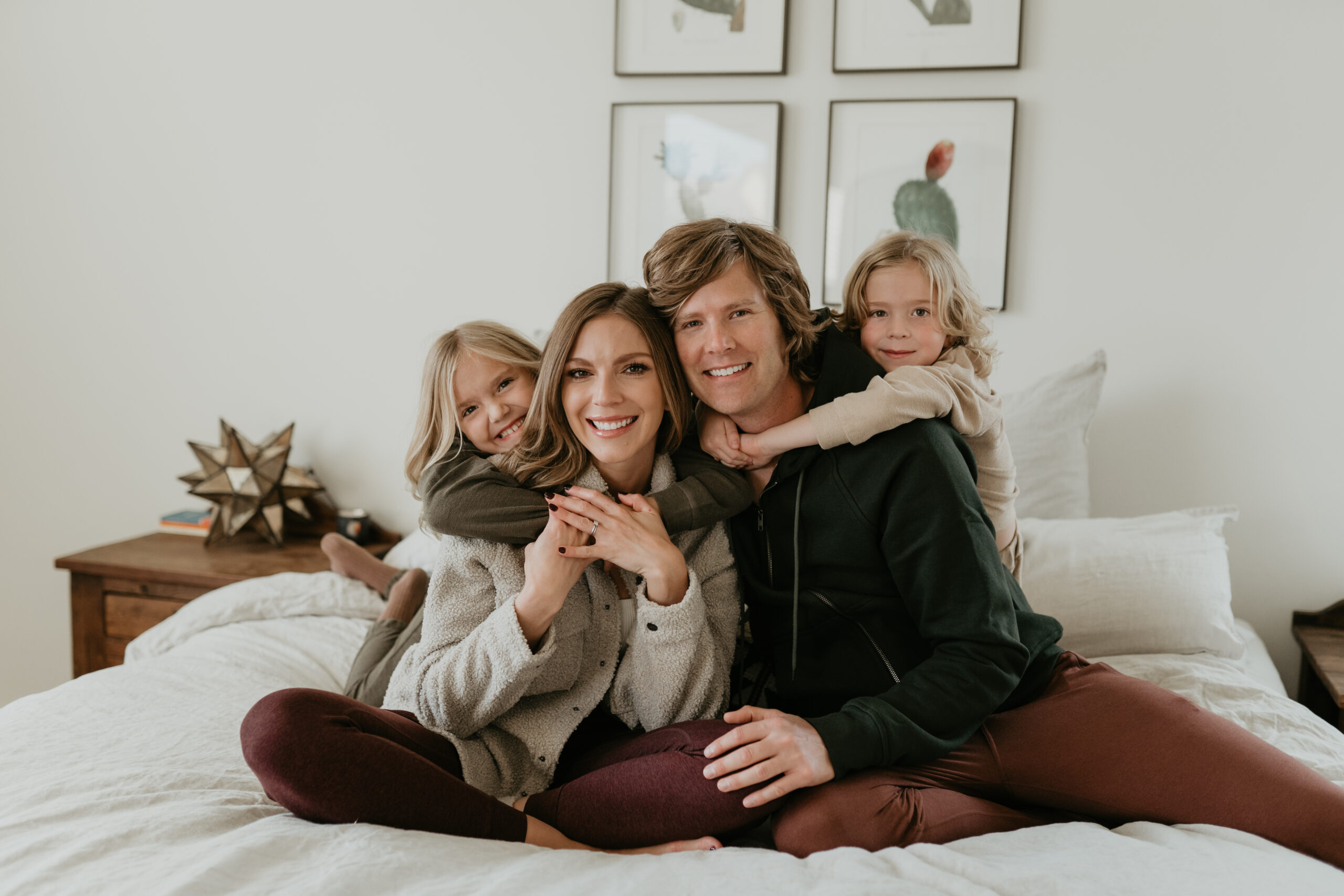 Family of four pose on the bed for their in home family photography in Tucson, Arizona by Alexa Rae Photo.